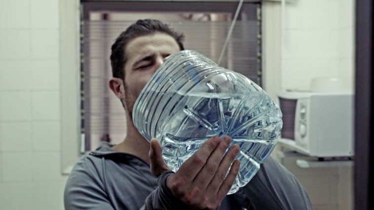 Un uomo assetato beve acqua da un bottiglione. I dolci fanno venire sete!