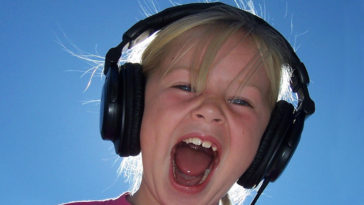 Bambina con cuffie che ascolta la sua voce