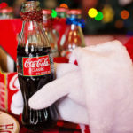 Babbo Natale tiene in mano una bottiglia piccola di coca cola