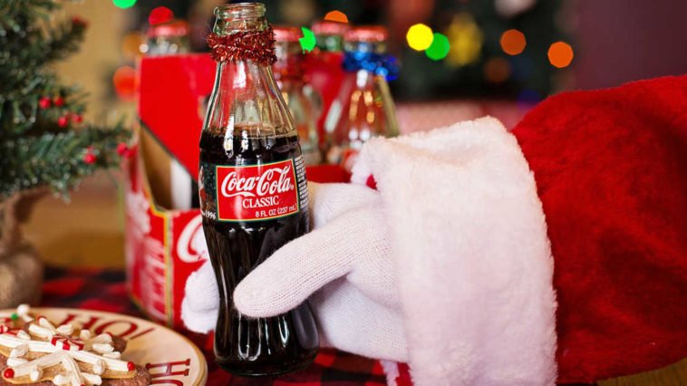 Babbo Natale tiene in mano una bottiglia piccola di coca cola