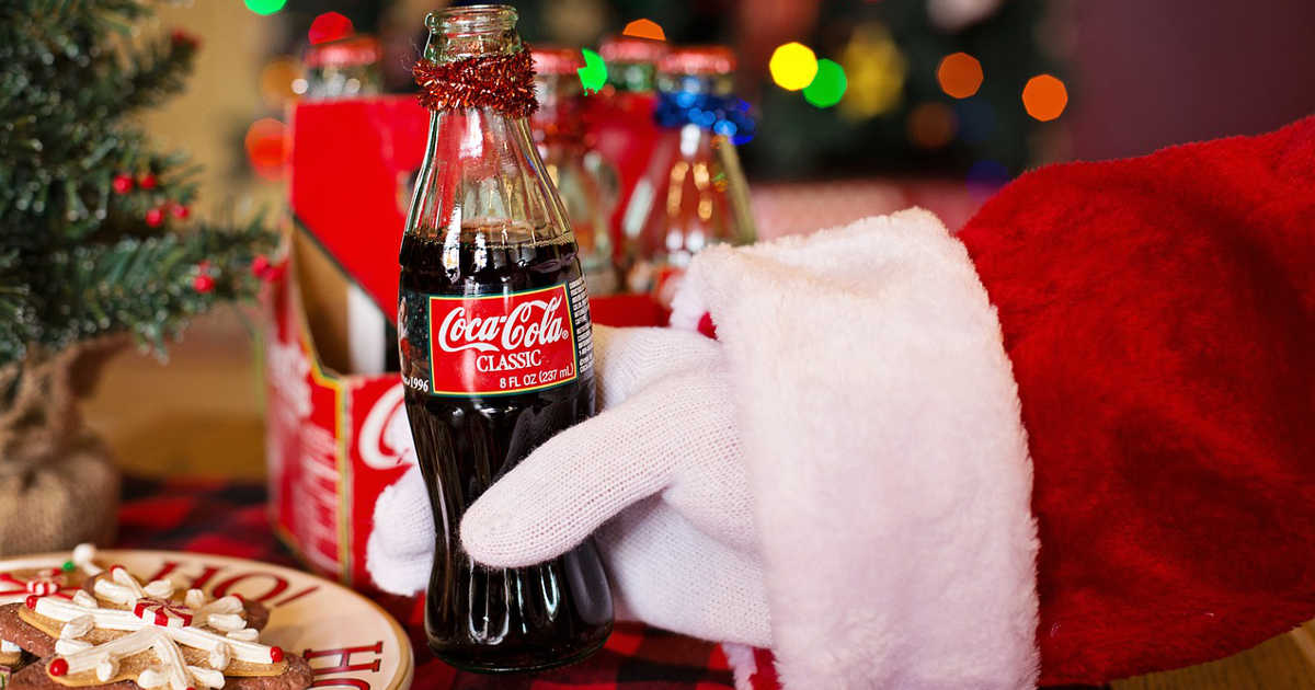 Babbo Natale tiene in mano una bottiglia piccola di coca cola