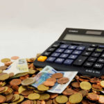 Una calcolatrice su una montagna di euro, sia monete che banconote, pronta a calcolare la liquidazione del TFR