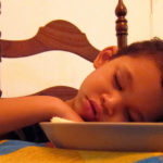 Bambino si addormenta al tavolo dopo aver mangiato un pasto abbondante che gli ha causato sonno