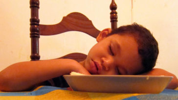 Bambino si addormenta al tavolo dopo aver mangiato un pasto abbondante che gli ha causato sonno
