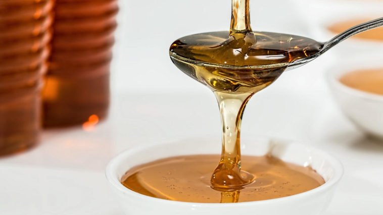 Miele versato con cucchiaino in tazza con latte