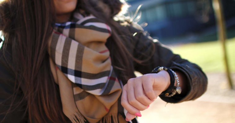 Ragazza con lunghi capelli guarda l'orologio da polso