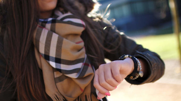 Ragazza con lunghi capelli guarda l'orologio da polso