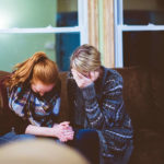 Donne che piangono su un divano consolandosi a vicenda