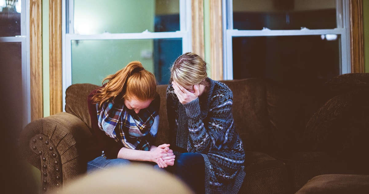 Donne che piangono su un divano consolandosi a vicenda