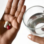 Un uomo ingoia una medicina in pillola con un bicchiere d'acqua ma ha paura di soffocare