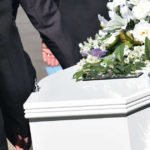 Funerale con persone che trasportano una bara bianca con dei fiori per dire condoglianze