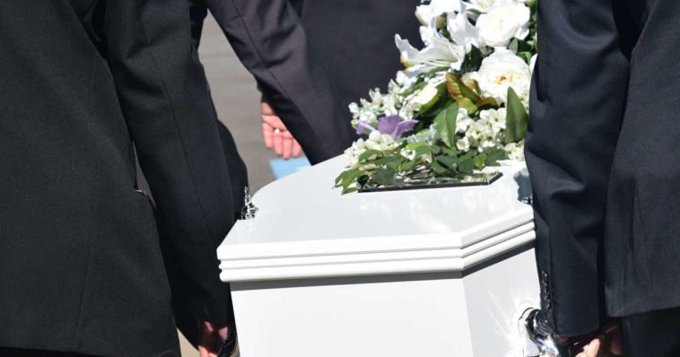 Funerale con persone che trasportano una bara bianca con dei fiori per dire condoglianze