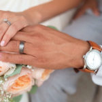 sposi che si tengono per mano tenendo bouquet e orologio