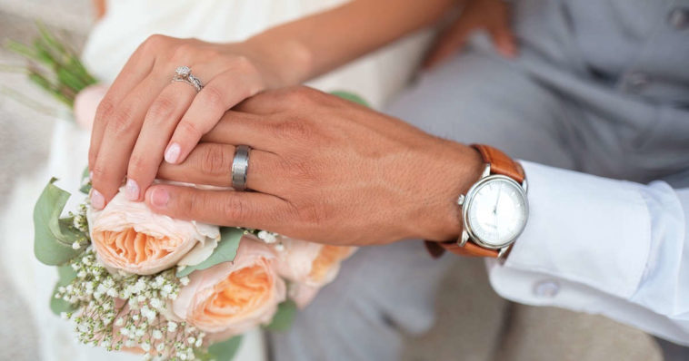 sposi che si tengono per mano tenendo bouquet e orologio