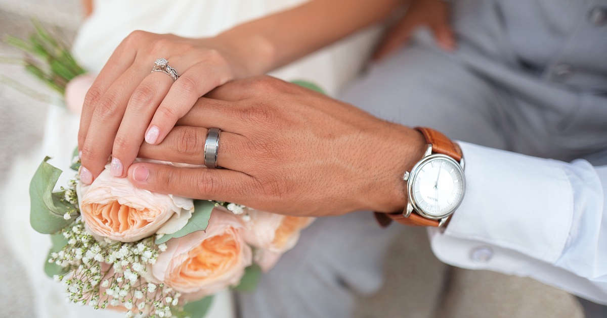sposi che si tengono per mano tenendo bouquet e orologio