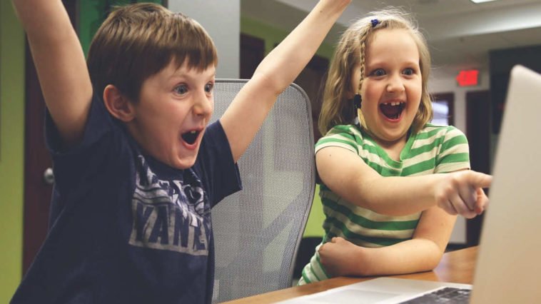 Dei bambini felici si divertono giocando al computer e il loro tempo è volato