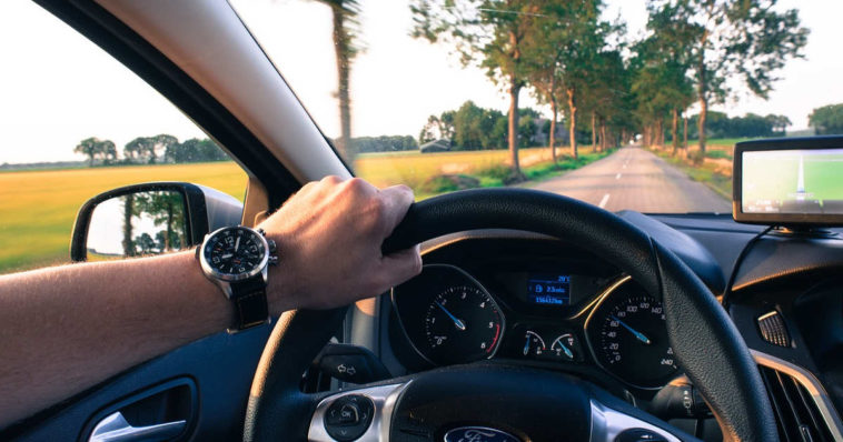 Uomo con orologio al polso guida un auto sul viaggio di ritorno che sembra più breve di quello dell'andata