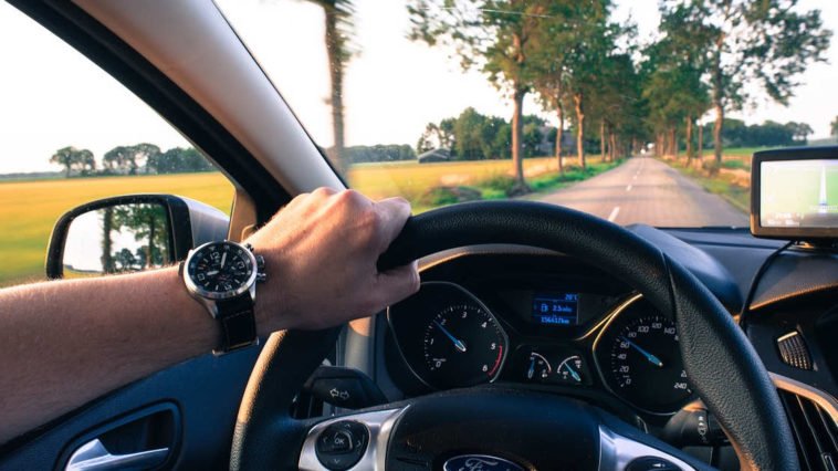 Uomo con orologio al polso guida un auto sul viaggio di ritorno che sembra più breve di quello dell'andata
