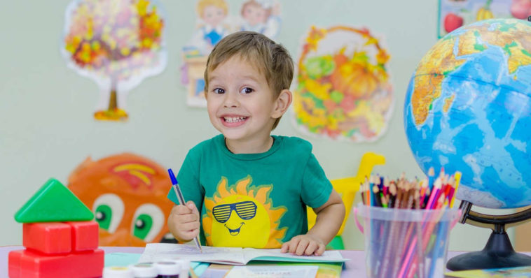 Bambino seduto al banco sorride felice di imparare nuove lingue straniere