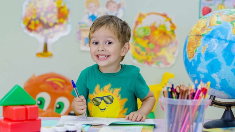 Bambino seduto al banco sorride felice di imparare nuove lingue straniere