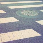 Un tombino tondo in mezzo alla strisce pedonali