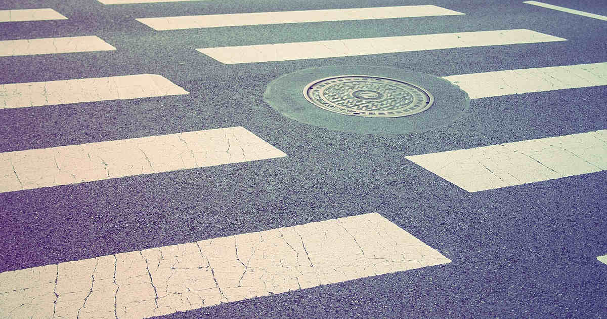 Un tombino tondo in mezzo alla strisce pedonali