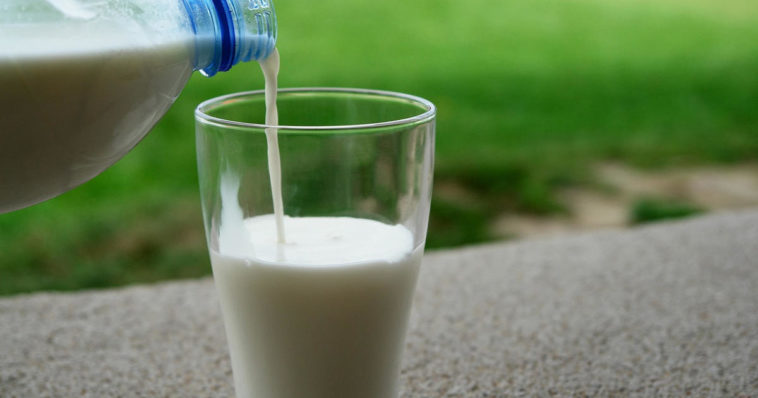 bicchiere di latte bianco versato da bottiglia