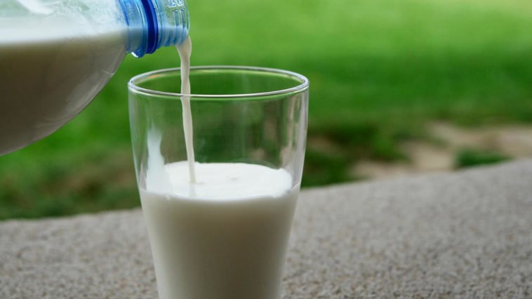 bicchiere di latte bianco versato da bottiglia