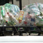 Un furgoncino bianco trasporta sul tetto dei sacchi pieni di bottiglie di plastica da riciclare