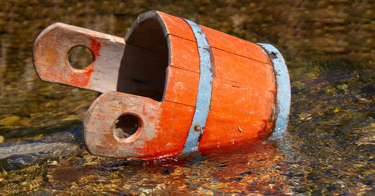 Un secchio di legno in pozza d'acqua